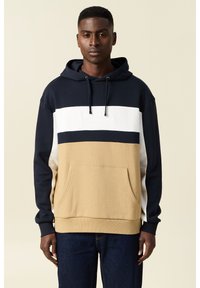 Felpa con cappuccio nei colori blu navy, bianco e beige, con blocchi di colore orizzontali, tasca frontale e cordino regolabile sul cappuccio.