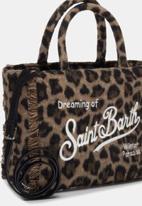 Bolsa de asa con estampado de leopardo, fabricada en lana beige y marrón, con detalles de flecos y una correa de cuero negro. Presenta texto blanco: "Soñando con el Paraíso Invernal de Saint Barth."