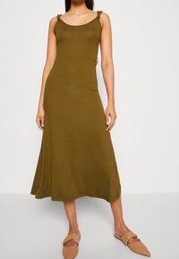 Olivově zelené bezramínkové šaty s těsným vrškem a rozšířenou sukní, s mašlemi na ramenech. Nosit s světlými béžovými balerínami.