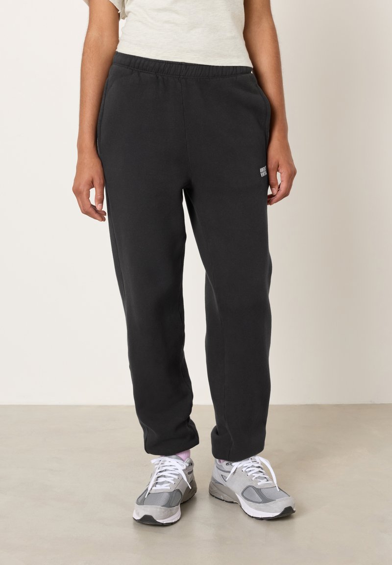 Juodos sportinės kelnės su elastinga juosmens juosta ir šoniniais kišenėmis. Lygi tekstūra, aptemptos prie kulkšnių, su mažo dydžio prekės ženklo logotipu šlaunyje.