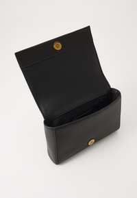 Svart lær clutch med en brett-over design, gull knappelukking og en glatt tekstur. Interiøret inkluderer kortlommer og en tom seksjon.