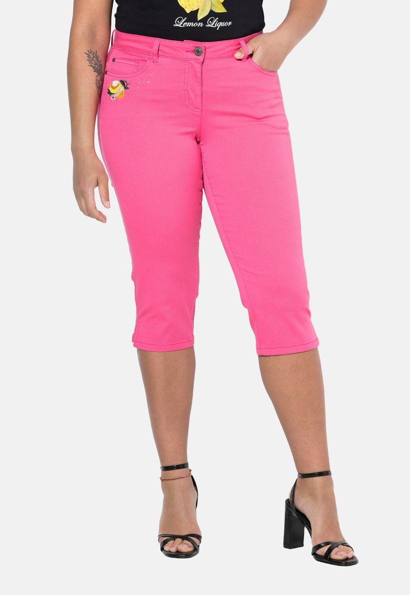 Vaaleanpunaiset farkku capri-housut, joissa on etutaskut, napitus ja brodeeraus lantiolla. Yhdistetty mustiin remmi-korkokenkiin.