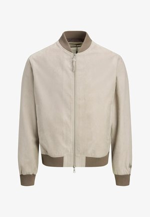 Vaaleanbeige bomber-takki, jossa on tummemman beigenväriset resorit hihansuissa, kauluksessa ja helmassa, etumuksessa vetoketju ja hillitty hihansuun kirjailu.