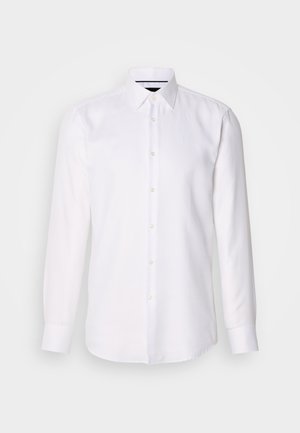 Chemise blanche à manches longues avec un motif de grille discret. Elle présente un col classique, une fermeture à boutons sur le devant et des poignets aux bords arrondis. Texture lisse.