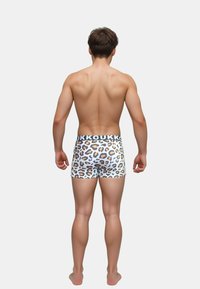 Leopardmönstrade boxershorts med vit bas och svart midjeband. Designen har orange och bruna fläckar, tillverkade av ett mjukt tyg.