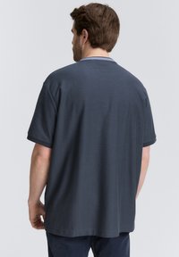 Donkergrijze T-shirt met korte mouwen, een ronde halslijn, een ontspannen pasvorm en een gladde textuur, van achteren weergegeven, met subtiele details.