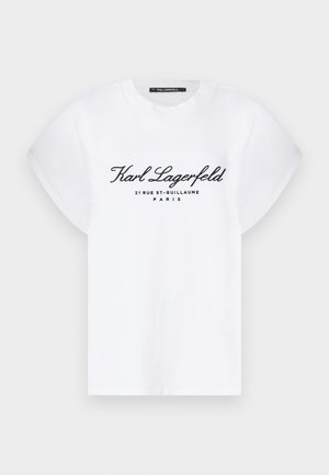 T-shirt en coton blanc à manches courtes et retroussées. Présente un texte noir : "Karl Lagerfeld 21 RUE ST-GUILLAUME PARIS" sur le devant.