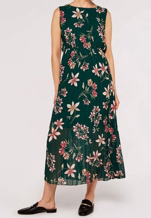 Robe midi sans manches vert foncé à imprimé floral rose et crème, jupe plissée, et mocassins noirs à enfiler sur fond blanc.