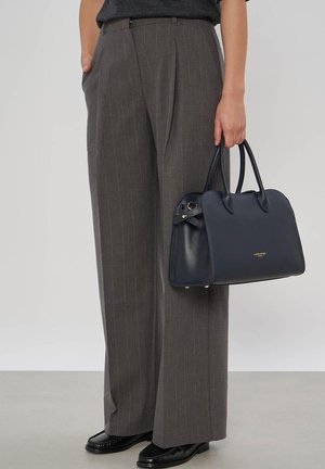 Person wearing gray pinstripe wide-leg trousers, black shoes, holding a structured navy handbag with double handles.