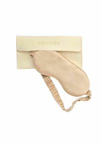 Světle béžová spací maska a pouzdro, vyrobené z měkké tkaniny. Pouzdro má vyražené písmo; maska má saténový povrch s elastickým popruhem.