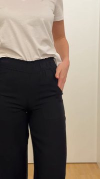 Άτομο που φοράει λευκό μπλουζάκι και μαύρο παντελόνι, με το ένα χέρι χαλαρά μέσα στην τσέπη του παντελονιού.