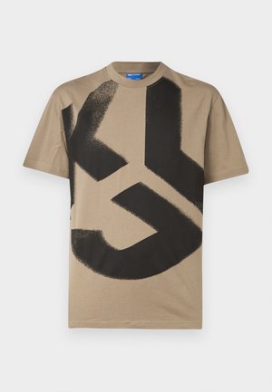 Beige cotton t-shirt featuring a large black abstract graphic design across the front. Round neckline, short sleeves, and relaxed fit.