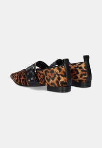 Zapatos de estampado de leopardo con una correa de cuero negro que presenta hebillas de plata. El diseño tiene punta afilada, tacón bajo y superficie texturizada.