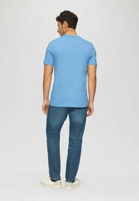Light blue short-sleeve t-shirt with a round neckline, paired with dark blue slim-fit jeans and white sneakers. Smooth fabric texture.