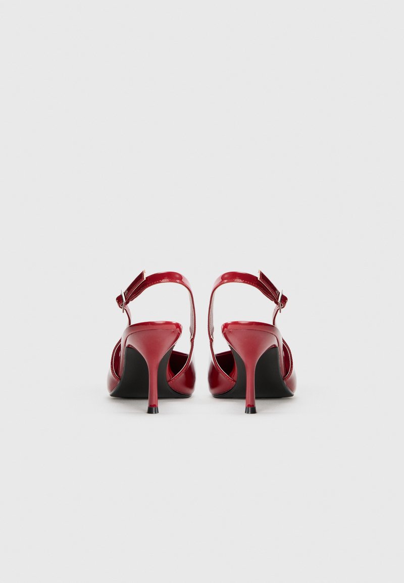 Sandali con tacco alto in pelle patent rossa, dotati di cinturino alla caviglia con fibbia regolabile, con punta affusolata e tacco sottile.