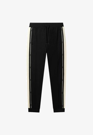 Černé sportovní kalhoty s krémovými postranními pruhy, elastickým pasem a manžetami. Disponují zipovými kapsami pro větší funkčnost.