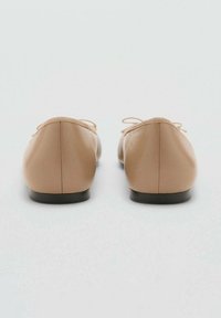 Naakte leren balletschoenen met een ronde neus, een elastische rand en een kleine zwarte zool. Eenvoudig ontwerp zonder zichtbare patronen of versieringen.