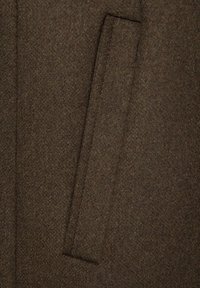 Brązowa tkanina z mieszanki wełny, charakteryzująca się gładką strukturą i prostokątną kieszenią po boku. Materiał ma subtelny, tkany wzór.