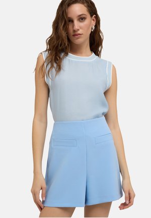 Hellblaues ärmelloses Oberteil mit weißem Besatz, kombiniert mit hochgeschnittenen hellblauen Shorts, die zwei Fronttaschen und eine glatte Textur aufweisen.