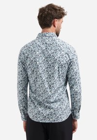 Lange mouwen shirt van lichtblauwe stof met een geometrisch patroon in navy en grijstinten; met knoopmanchetten en een detail op de rug.