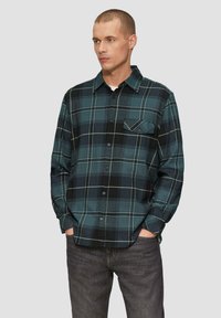 Zielono-czarna koszula flanelowa w kratę z długimi rękawami, zapinana na guziki, z jedną kieszenią na piersi. Wykonana z miękkiego materiału, w swobodnym kroju.