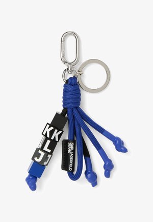 Llavero con cuerdas azules anudadas, cuentas negras y blancas con letras, una etiqueta de "Karl Lagerfeld Jeans" y un broche y anillo de metal plateado.