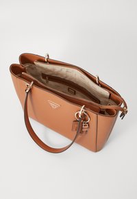 Borsa tote beige con finitura testurizzata, hardware dorato e doppi manici. Presenta una parte superiore aperta con più scomparti e un accento del logo.