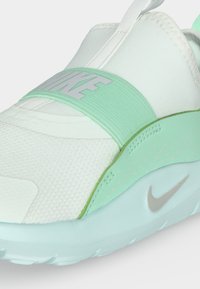 Λευκό και μέντα πράσινο sneaker Nike slip-on με ελαστικό λουράκι στο πάνω μέρος και ορατό λογότυπο Nike στη σόλα και το λουράκι.