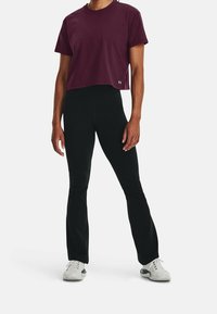 Vinröd kortärmad sportt-shirt med rund hals, kombinerad med svarta utsvängda byxor. Outfitten har lätt, andningsbart tyg och en figurnära design.