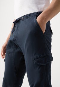 Mörknavy cargobyxor i lättviktsmaterial, med elastisk midja och dragsko samt flera sidfickor.