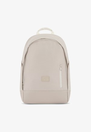 Zaino in tessuto beige con parte superiore arrotondata, fondo piatto, tasca anteriore con zip e una piccola etichetta logo. Presenta spallacci doppi e una maniglia superiore.