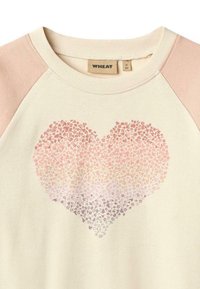 Cremefarbenes Sweatshirt mit hellrosa Raglanärmeln, das ein Herzdesign aus kleinen Blumenmustern zeigt, das von Pink zu Lavendel übergeht.