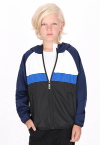 Windbreaker-Jacke in Schwarz, Weiß und Blau mit durchgehendem Reißverschluss, Kapuze und elastischen Bündchen. Hergestellt aus leichtem, glattem Material.