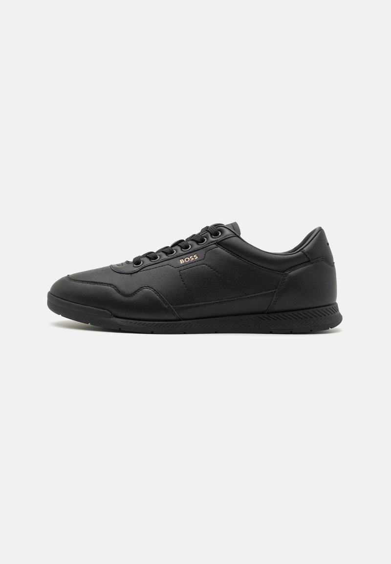 Black leather sneaker with a smooth texture, featuring a lace-up design, subtle branding, and a rubber sole with a patterned tread.