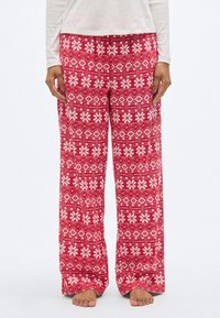Pantalon de détente rouge à motifs avec des dessins floraux et géométriques blancs, fabriqué en tissu doux avec une coupe ample et une taille élastique.