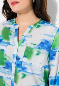 Camicia a maniche lunghe in tessuto leggero con un motivo ad acquerello blu e verde, con colletto a pizzico e due tasche frontali.