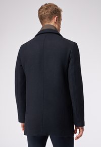 Cappotto di lana navy con vestibilità su misura, colletto a punte e texture liscia. Presenta un design pulito sul retro e dettagli di cucitura sottili.
