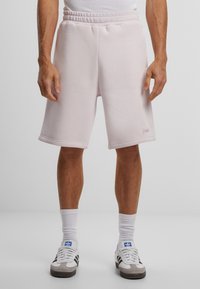 Lyserøde treningsshorts med elastisk midje, sidelommer og en liten logo-detajl. Laget av mykt stoff med en jevn tekstur.