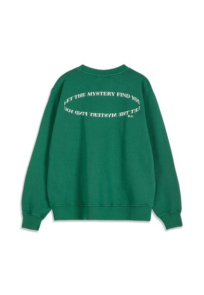 Sweat-shirt vert avec un texte blanc incurvé au dos indiquant "LET THE MYSTERY FIND YOU" deux fois, avec de petites initiales "B.C." à la fin.