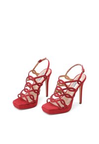 Sandali con tacco alto rossi, con cinturini incrociati, caratterizzati da una texture scamosciata, punta aperta e suola platform per un'altezza aggiuntiva.