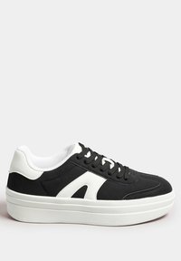 Svart sneaker med vit detalj, rund tå, texturerad ovansida, svarta snören och en tjock vit sula. Slät tyg kontrasterar med matta sektioner.