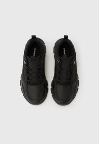 Ζευγάρι μαύρα chunky sneakers με ταινίες έλξης, χοντρές σόλες και κορδόνια σε απλό λευκό φόντο.