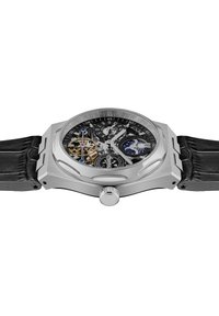 Luksusowy zegarek z obudową ze stali nierdzewnej w kolorze srebrnym, czarną tarczą, odsłoniętymi mechanicznymi zębatkami oraz czarnym skórzanym paskiem. Posiada srebrne akcenty i koronę.