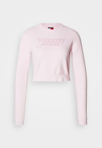 Maglione corto in maglia rosa chiaro con maniche lunghe e scollo rotondo. Logo "Tommy Jeans" impresso sul davanti. Texture morbida.