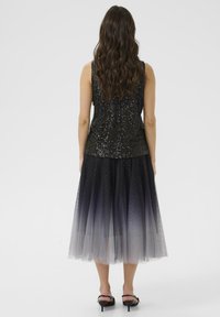 Black sequin top with sleeveless design paired with an ombre tulle skirt, transitioning from dark to light grey, featuring subtle sparkles.