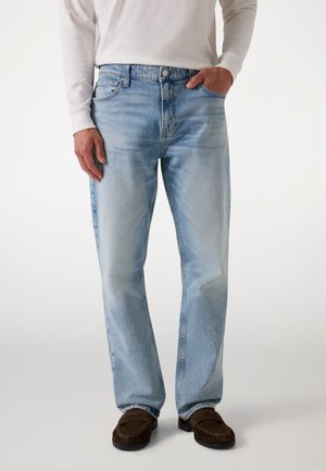 Light blue denim jeans with a relaxed fit, five-pocket design, faded texture, and metal button closure, paired with brown loafers.