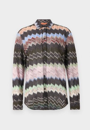Camicia a maniche lunghe con motivo a zigzag in nero, blu, rosa, verde e beige, con chiusura frontale a bottoni e colletto classico su sfondo bianco.