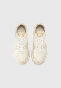 Une paire de baskets beige et blanche Michael Kors avec un motif en monogramme MK et des accents en logo doré, vue du dessus sur un fond clair.