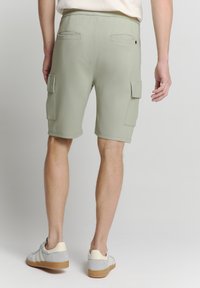 Lichtgroene cargoshorts gemaakt van rekbaar materiaal, met twee zijzakken en twee achterzakken, een eenvoudige zoom en een getailleerde pasvorm.