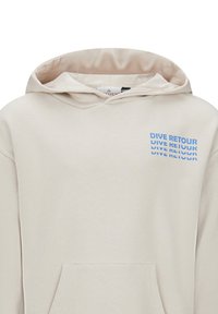 Beige hoodie gemaakt van zachte stof, voorzien van een voorvak en een trekkoordcapuchon. Op de voorkant staat de tekst "DIVE RETOUR" in het blauw.